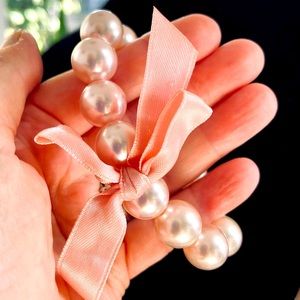 Pink pearls and ribbon on elastic bracelet.